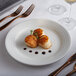 A Tuxton Pacifica bright white china plate with scallops and a fork on it.