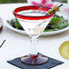 A Libbey martini glass with a red rim and base filled with a drink and olives.