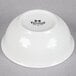 A white Tuxton China bowl with black text on it.
