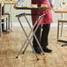 A man using a Lancaster Table & Seating chrome metal double bar tray stand to hold a tray of food.