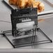 A countertop rack holding a clear plastic bag of chicken with a black label.