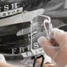 A person in gloves using a clear plastic clip to close a bag on a countertop.