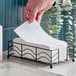 A stack of white linen-feel guest towels in a black metal holder on a bathroom counter.