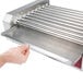 A hand holding a Grand Slam metal replacement drip tray under a hot dog roller.