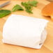 A white paper bag with a sandwich wrapped in 12" x 15" heavy duty dry wax paper.