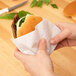 A person holding a burger wrapped in 12" x 15" heavy duty dry wax paper.