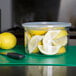 A Carlisle clear plastic crock filled with lemons and a knife.