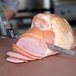 A Waring electric knife cutting a ham on a cutting board.