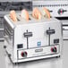 A Waring commercial toaster with three slices of bread inside.