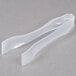 A pair of clear plastic tongs on a gray surface.