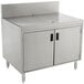A stainless steel Advance Tabco enclosed drainboard cabinet with doors over a drain.