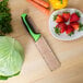 A Mercer Culinary Produce Knife in a leather sheath on a table with vegetables.