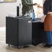 A woman and a man standing next to a black Galaxy Single Tap Kegerator Beer Dispenser on wheels.