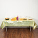 A table with a Creative Converting gold metallic plastic table cover and food on it.