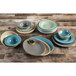 A stack of Elite Global Solutions Hemlock melamine bowls on a table with plates and other bowls.