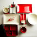 A white table set with red and black Elite Global Solutions rectangular two-tone melamine plates and bowls.