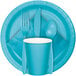 A blue plate with a Bermuda Blue Creative Converting beverage napkin, a fork, spoon, and knife.