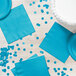 A table with Bermuda blue paper napkins and confetti.