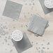 A stack of Shimmering Silver 2-ply beverage napkins on a table.