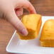 A person holding a piece of cake on a white GET Midtown rectangular melamine platter.