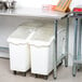 A stainless steel Advance Tabco open base work table with white plastic containers on it.