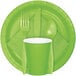 A green paper napkin with a fork and spoon on a white surface.