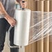 A large roll of clear Lavex 20" x 5000' 80 gauge machine pallet wrap or stretch film being dispensed by a person.