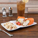 A white melamine platter with a sandwich and tortilla wrap on it.