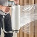 A roll of pre-stretched hand pallet wrap film being dispensed with a handle.