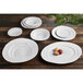 A group of white irregular round bowls on a wooden table.