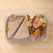 A sandwich and chips in a 10" x 7" Tamper Evident clear plastic container.