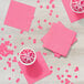 A group of cups of drinks and pink napkins on a table.