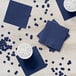 A white table with a blue napkin and cup of water on it.