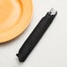 A fork in a black velvet paper dinner napkin on a plate.