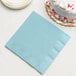 A pastel blue paper dinner napkin next to a white cake.