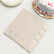 An ivory Creative Converting paper dinner napkin next to a white cake with red sprinkles.