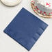 A navy blue paper napkin next to a white cake.