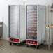 A white Avantco holding cabinet with a clear glass door holding trays of doughnuts.