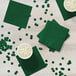 A close up of a Hunter Green Creative Converting beverage napkin on a table with cups of liquid.