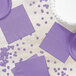 A table set with a white cake, purple plates, and a Luscious Lavender purple napkin with polka dots.
