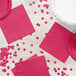 A table with pink napkins and confetti.