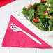 A plate of salad with strawberries, nuts, and a fork on a napkin.