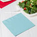 A pastel blue luncheon napkin with a fork on a plate of salad.