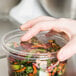 A hand holding a Choice plastic deli container of food