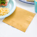 A blue plate with macaroni and cheese and a Glittering Gold luncheon napkin.