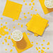 A table with yellow luncheon napkins and drinks.