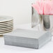 A stack of white Creative Converting Shimmering Silver luncheon napkins.