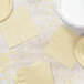 A table set with a white cake and ivory Creative Converting 1/4 fold luncheon napkins.