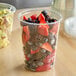A clear 32 oz. plastic deli container filled with assorted fresh berries including strawberries, blueberries, and blackberries.