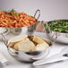 An American Metalcraft stainless steel balti dish with pasta and bread on a table.